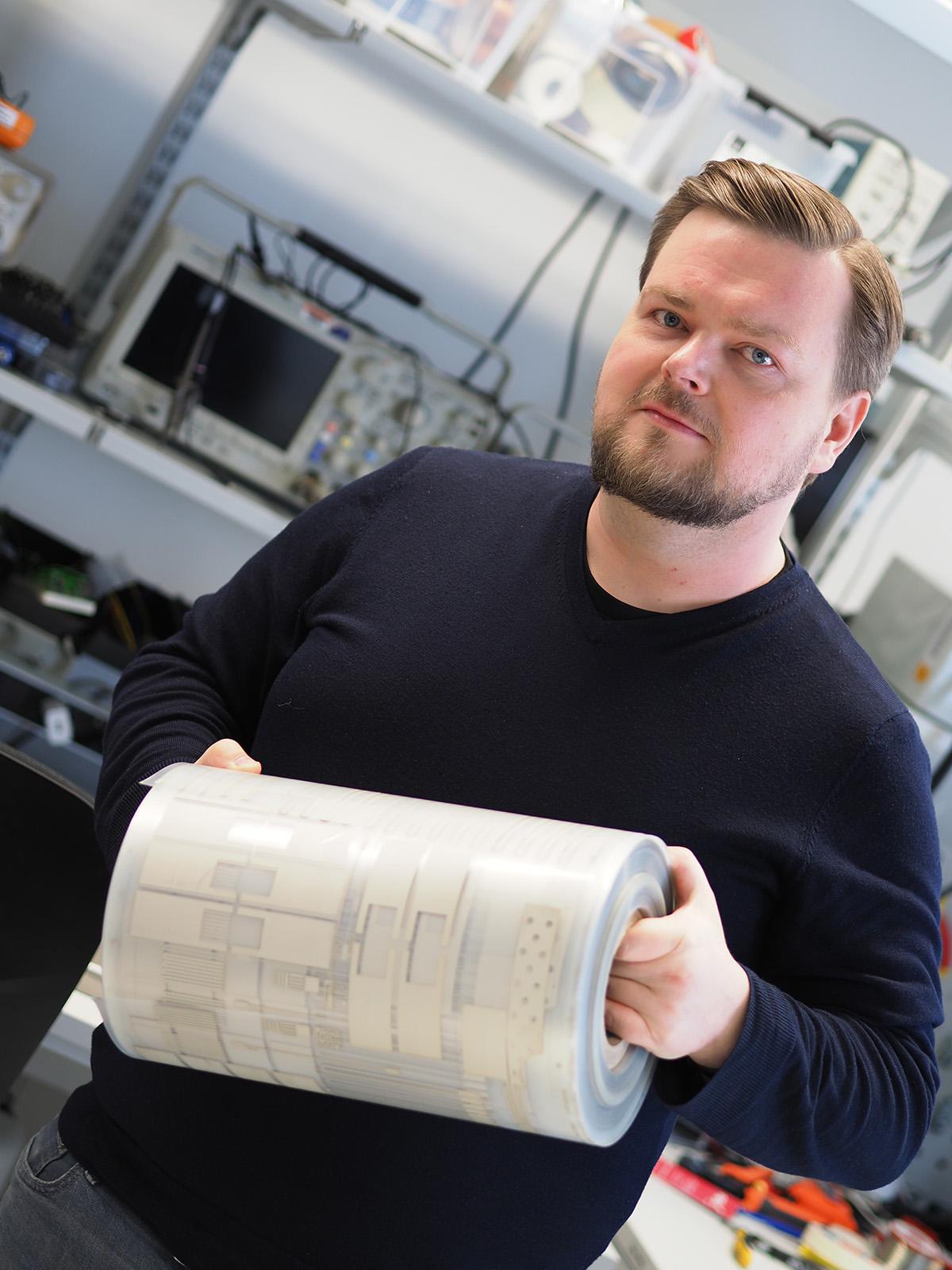 Solution Architect Toni Liimatta with a stack of printed electronics.